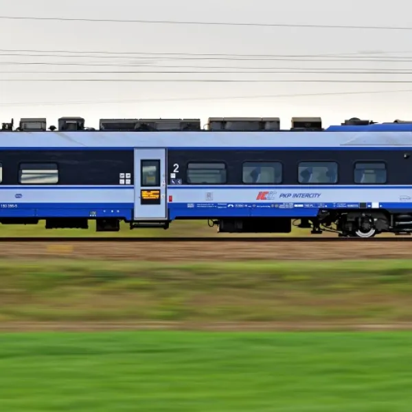 High-speed blue train traveling through countryside.